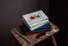 Pile of books, coloured notebooks and pencil on a wooden stool